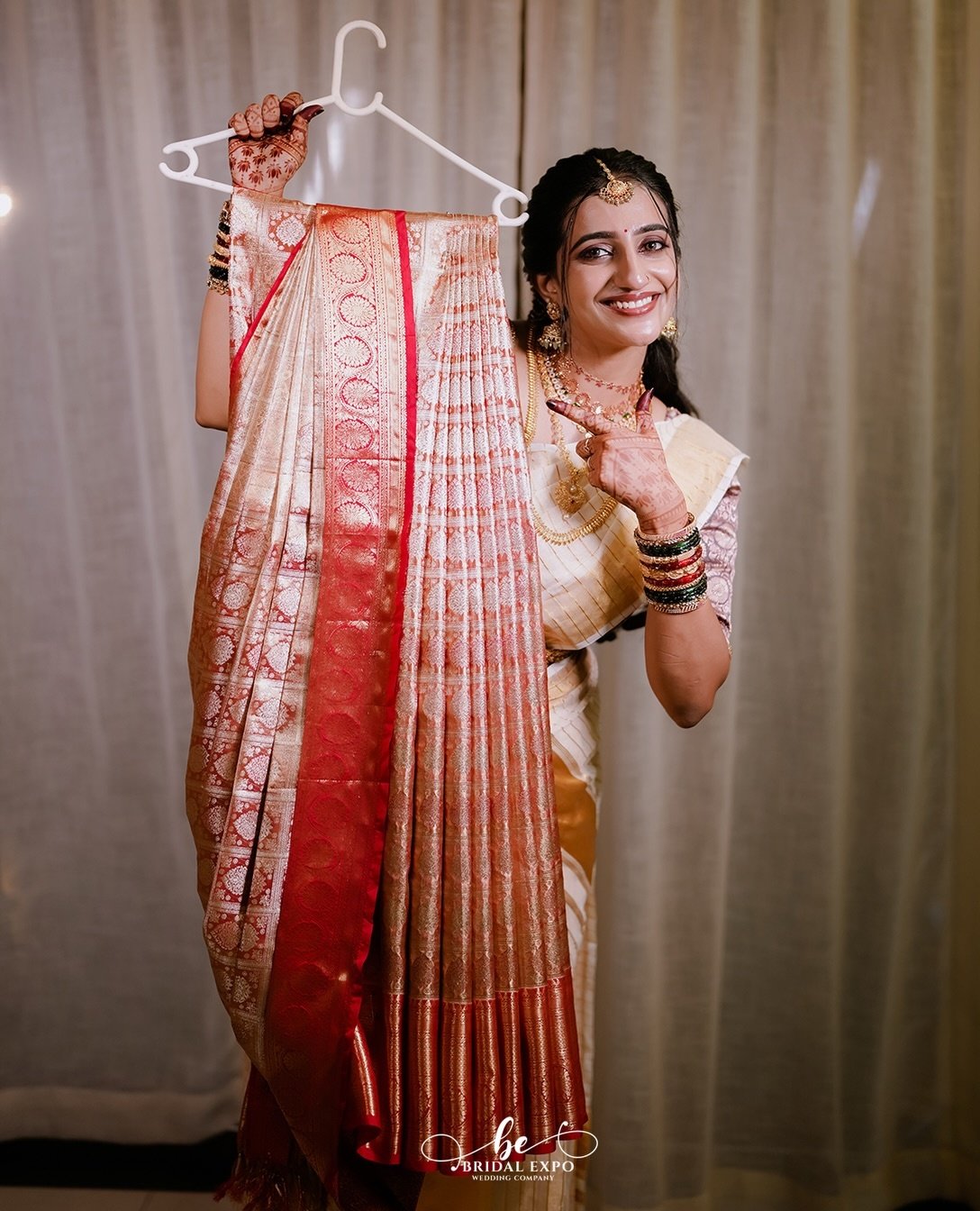 A bride smiling joyfully holding her wedding attire