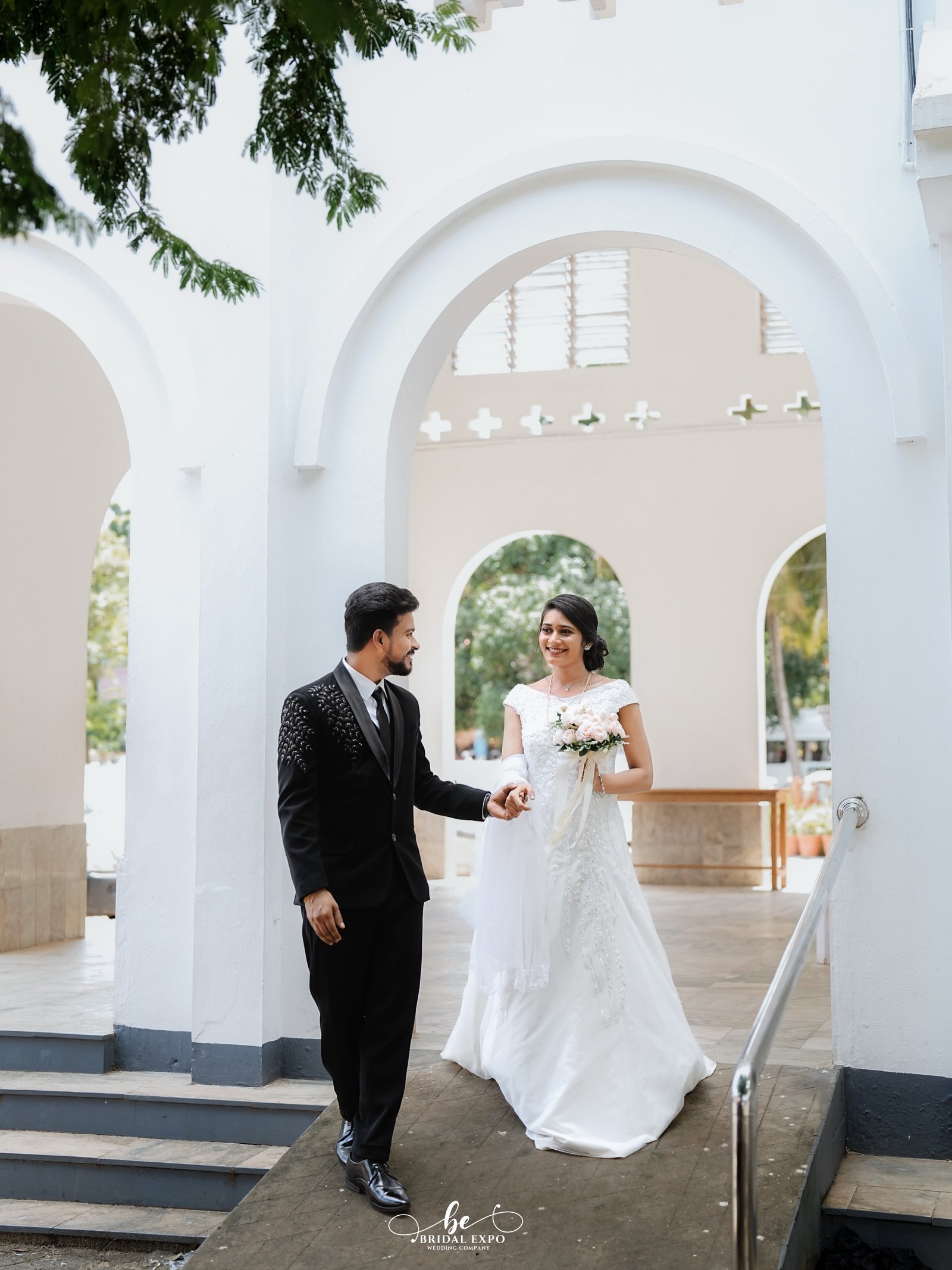 A bride and groom walking hand in hand in celebratory attire